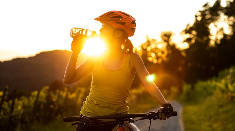 En kvinna på en cykel i solnedgång