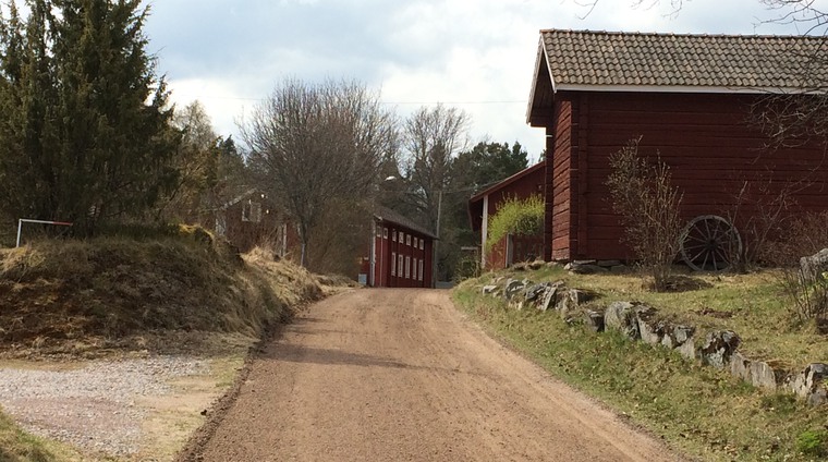 En grusväg som går mellan röda hus